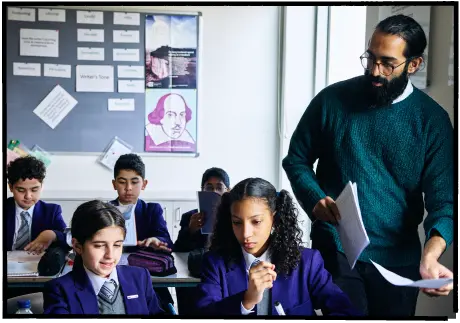 A teacher handing out worksheets to pupils in a classroom
